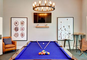 a games room with a blue pool table and a tv at Deer Creek Apartments, Puyallup, 98373